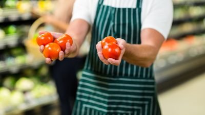mid-section-of-worker-showing-vegetables-in-supermarket.jpg